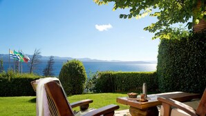 A patio with two wooden chairs and a table, overlooking a body of water and mountains. - Pailahue Lodge & Cabañas (San Carlos de Bariloche)