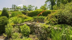 Ein Garten mit einer Steinbrücke, üppigem Grün und einem kleinen Teich.
