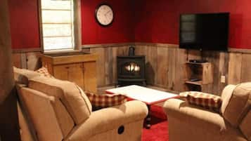 A cozy room with a wooden cabinet, a fireplace, a television, and two beige armchairs.