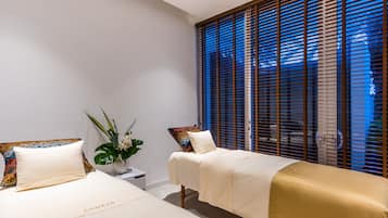 Two single beds and a single bed with a gold accent, set in a minimalist room with a large window and a potted plant.