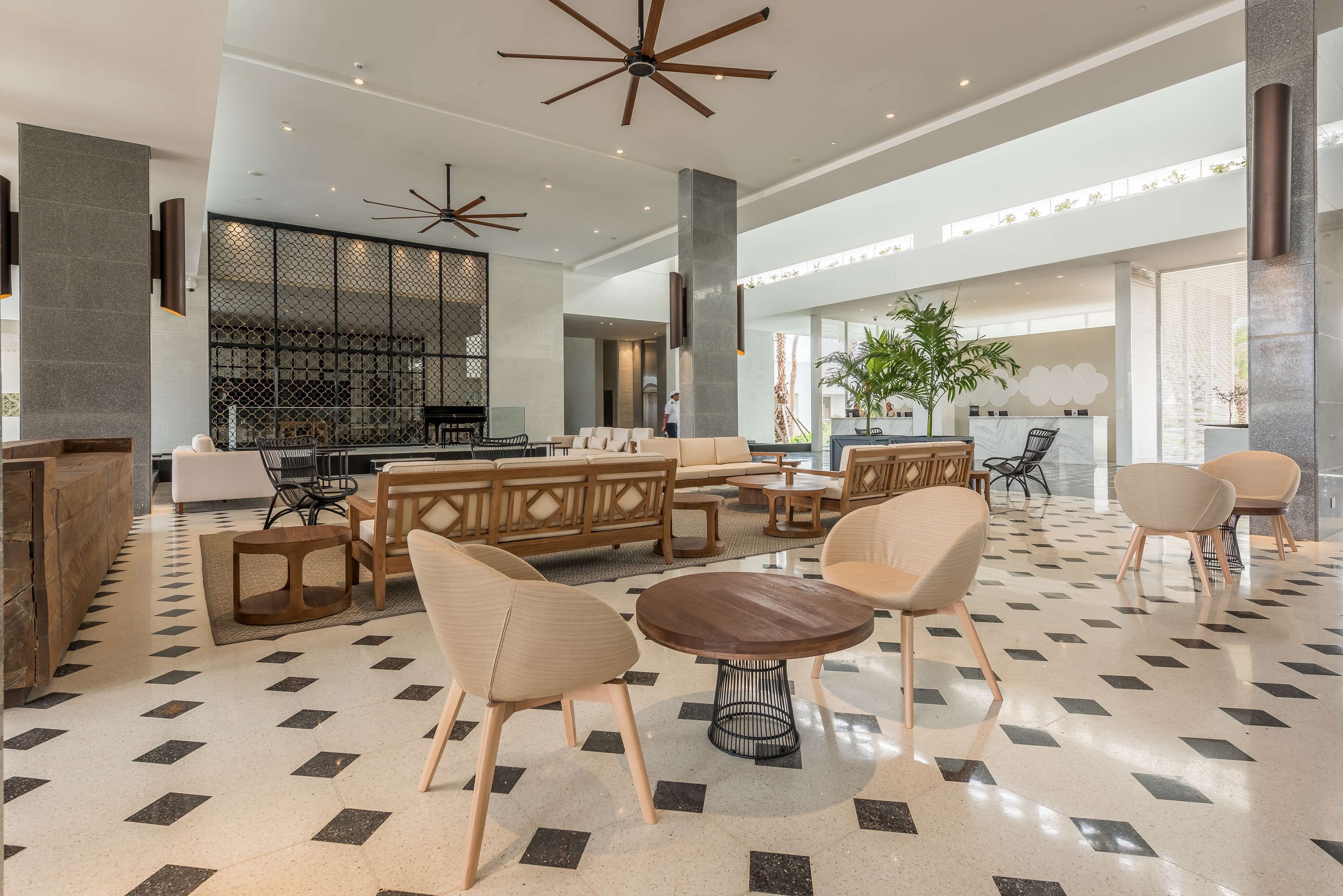 A spacious lobby with a checkered floor, modern furniture, and a large ceiling fan.