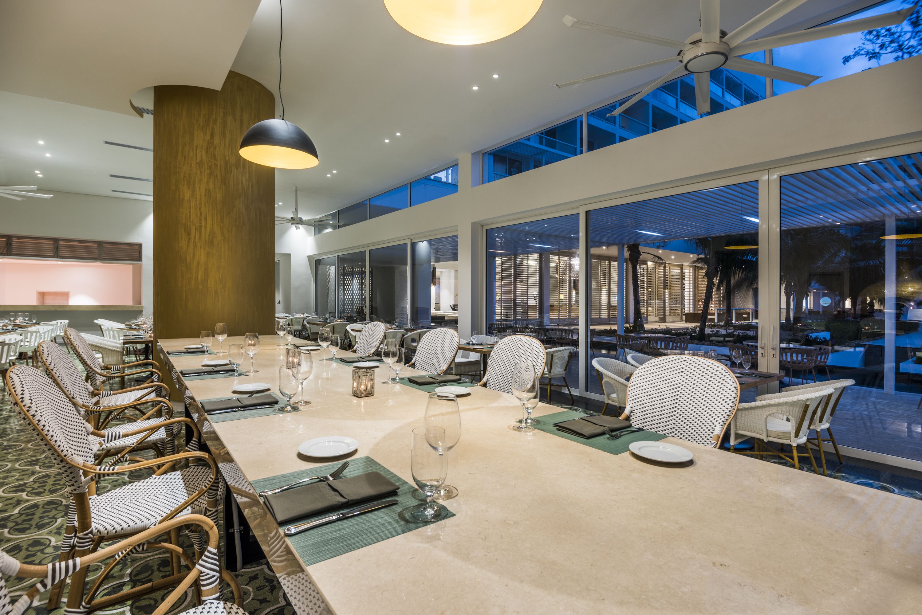 Un comedor amplio con techos altos, ventanas grandes y vistas al exterior.