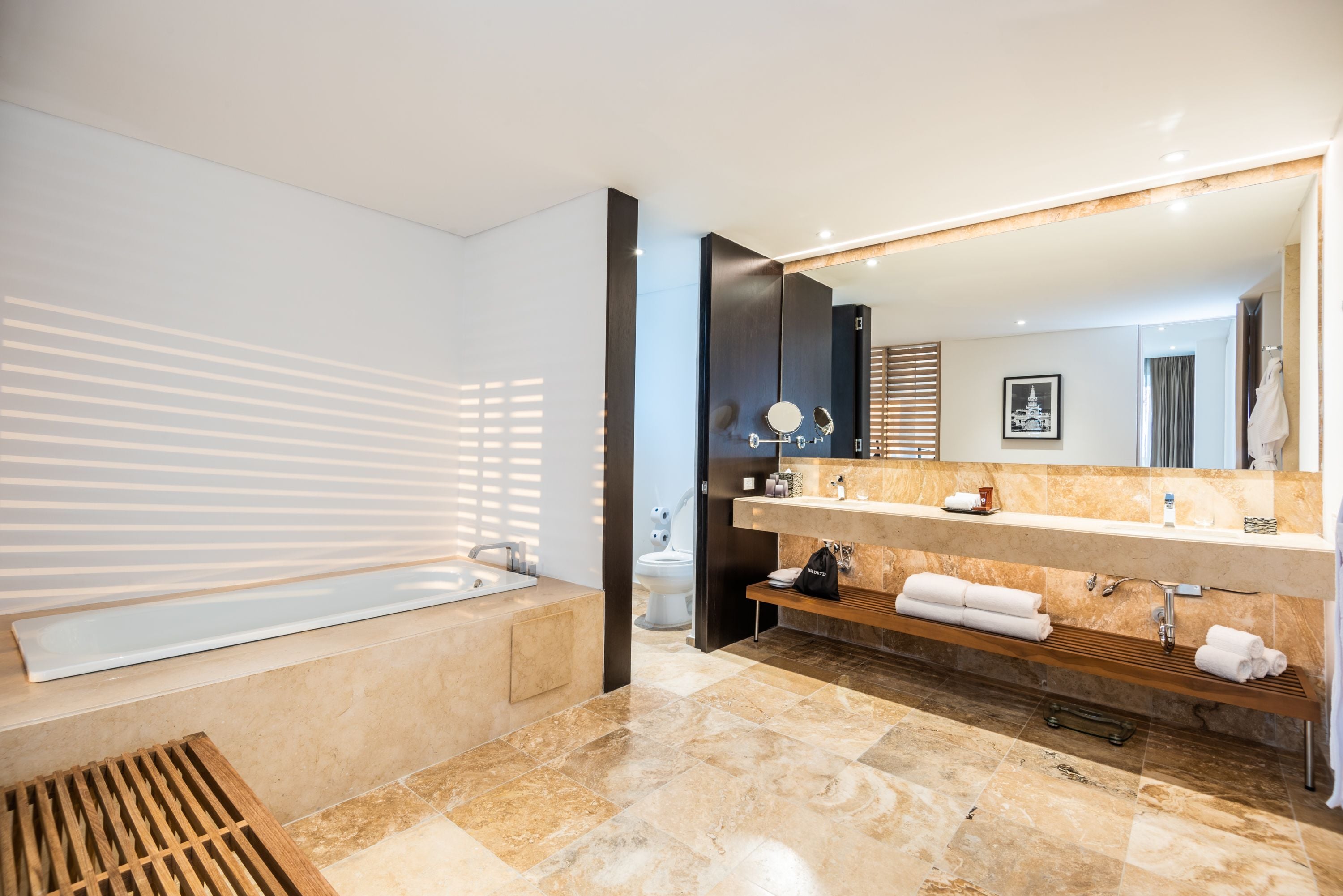 A modern bathroom with a large bathtub, dual sinks, and a vanity with a mirror.
