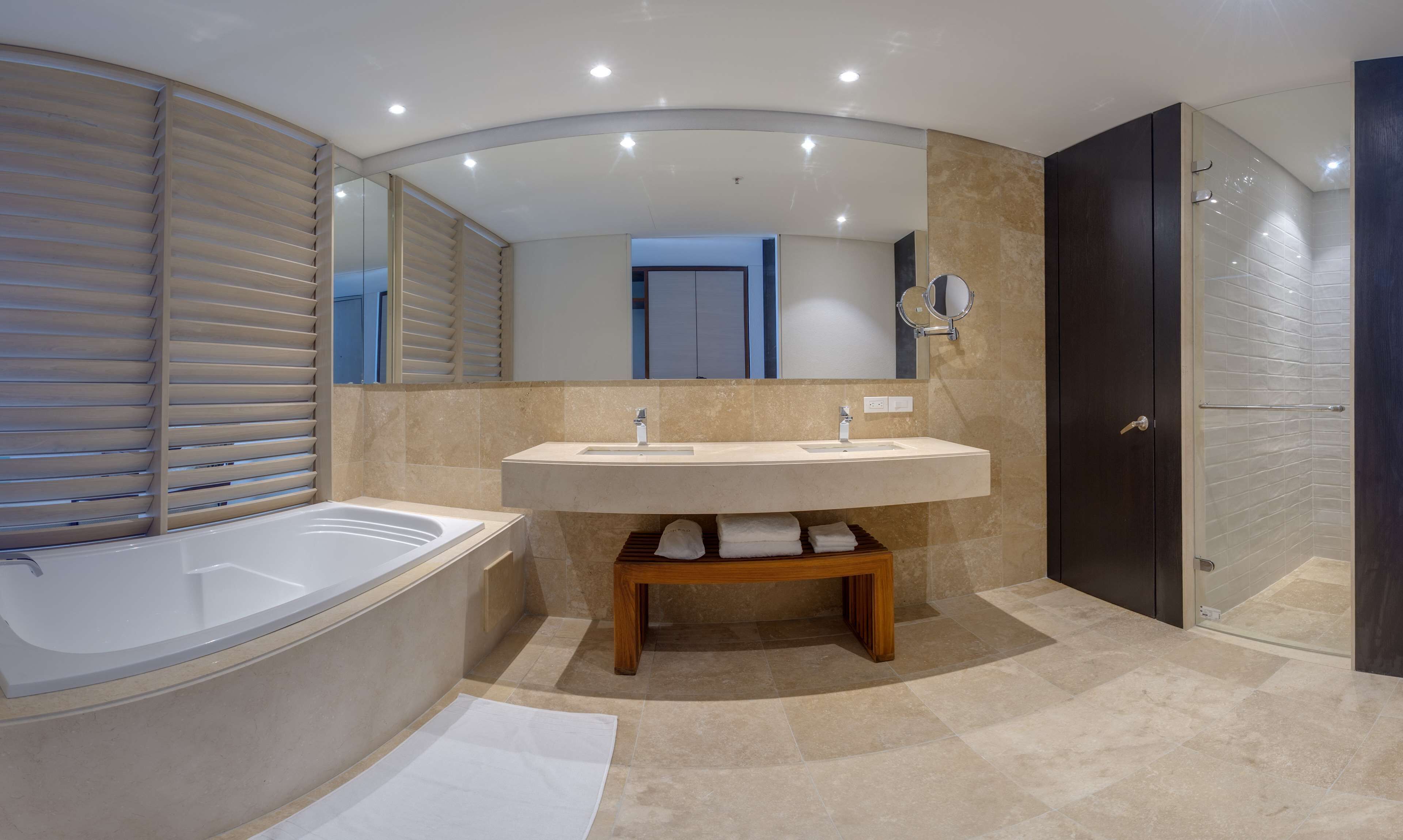 A modern bathroom with a freestanding bathtub, a double sink vanity, a large mirror, and a walk-in shower.