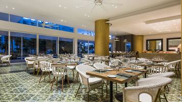 A spacious dining area with high ceilings, large windows, and a modern chandelier.
