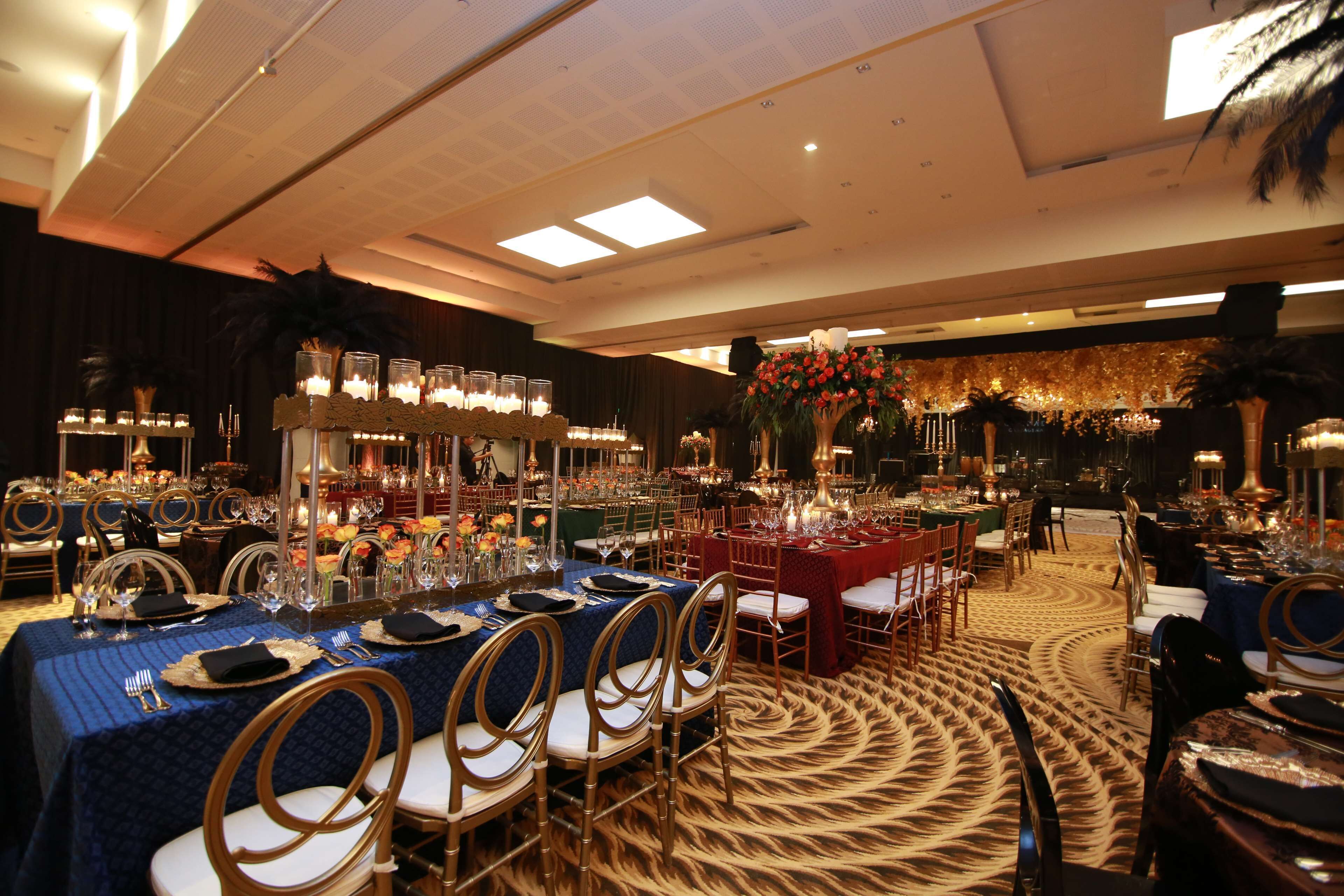 A banquet hall with round tables, chairs, and floral centerpieces.