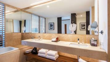 Un baño moderno con un espejo grande, dos lavamanos y una bañera.