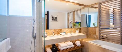 A modern bathroom with a glass-enclosed shower, a double sink vanity, and a bathtub.