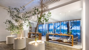 Een modern interieur met grote potplanten, een glazen scheidingswand en uitzicht op de stad.