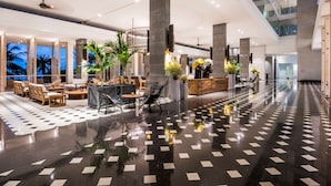 Een ruime lobby met een glanzende zwart-wit betegelde vloer, modern meubilair en grote pilaren.