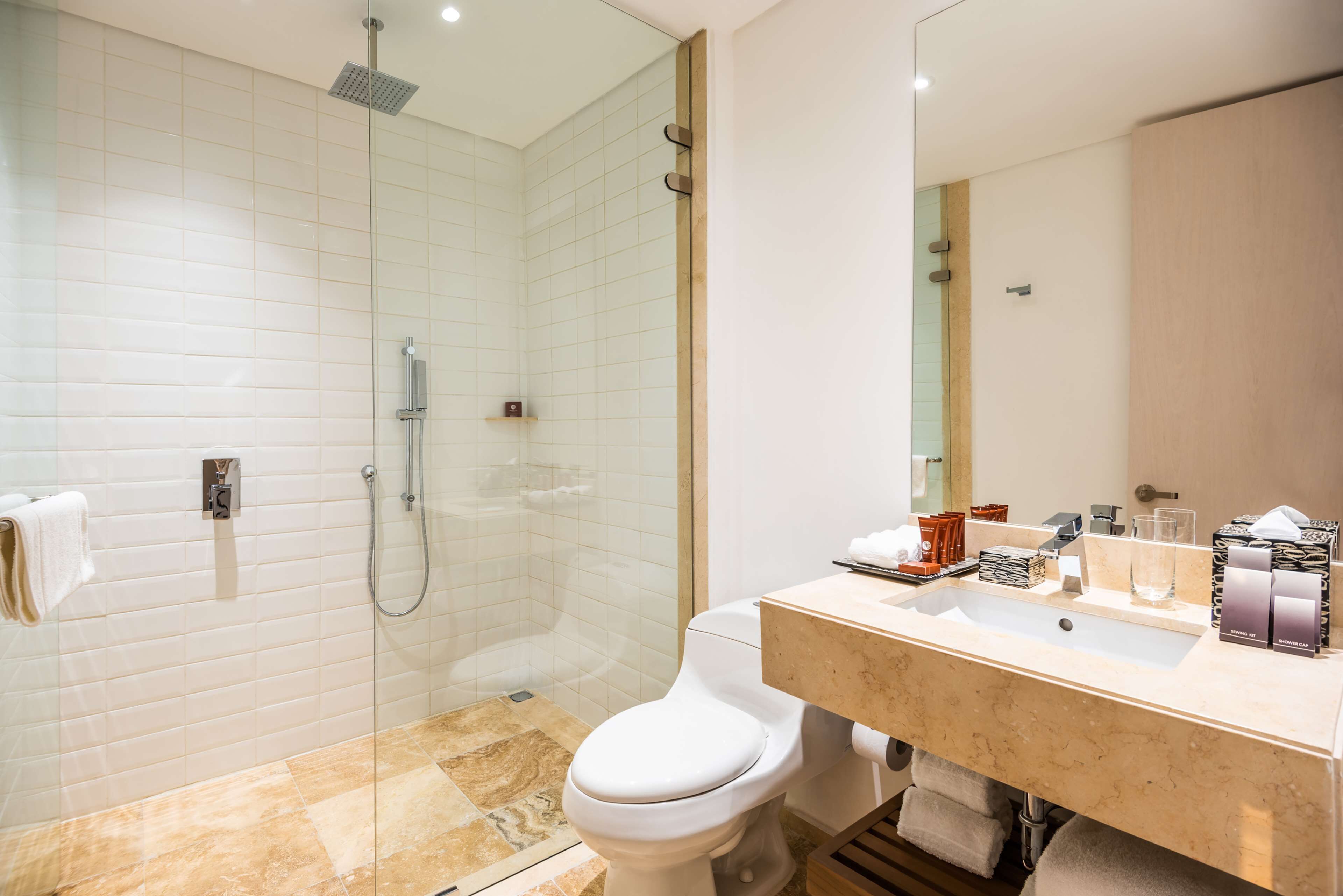 Une salle de bain moderne avec une douche à parois de verre, des toilettes blanches et un sol carrelé en marbre.