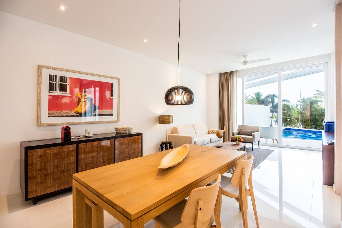 Un salon moderne avec une table à manger en bois, un canapé et une grande fenêtre donnant sur une piscine.