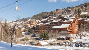A ski resort with wooden buildings, a cable car, and a parking area. - Maeva Particuliers - Résidence Les Ravines (Les Allues)