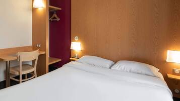 A hotel room with a bed, a desk, a chair, and two bedside lamps.