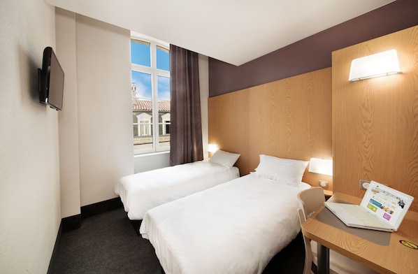 A hotel room with two beds, a desk with a laptop, a TV mounted on the wall, and a window with curtains. - B&B HOTEL Castres Centre Gambetta (Castres)