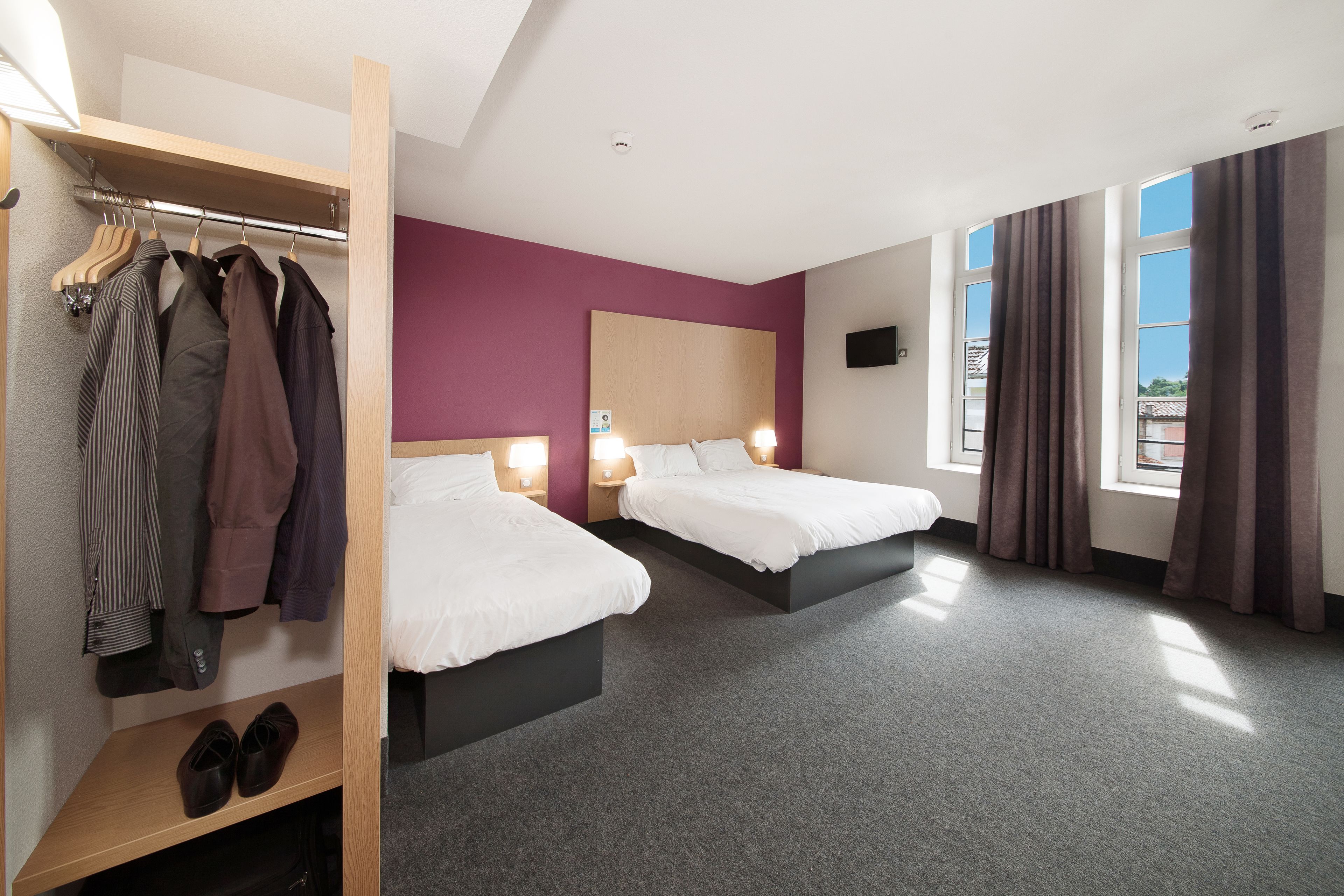 Una habitación de hotel con dos camas, un armario y un estante para zapatos.