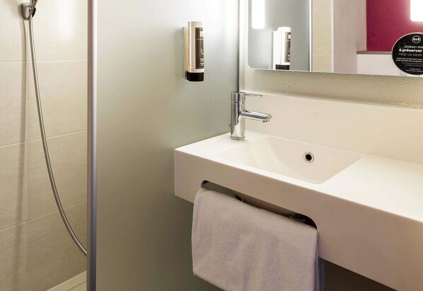 Un baño con un lavamanos blanco, un espejo y una toalla colgada en la pared.