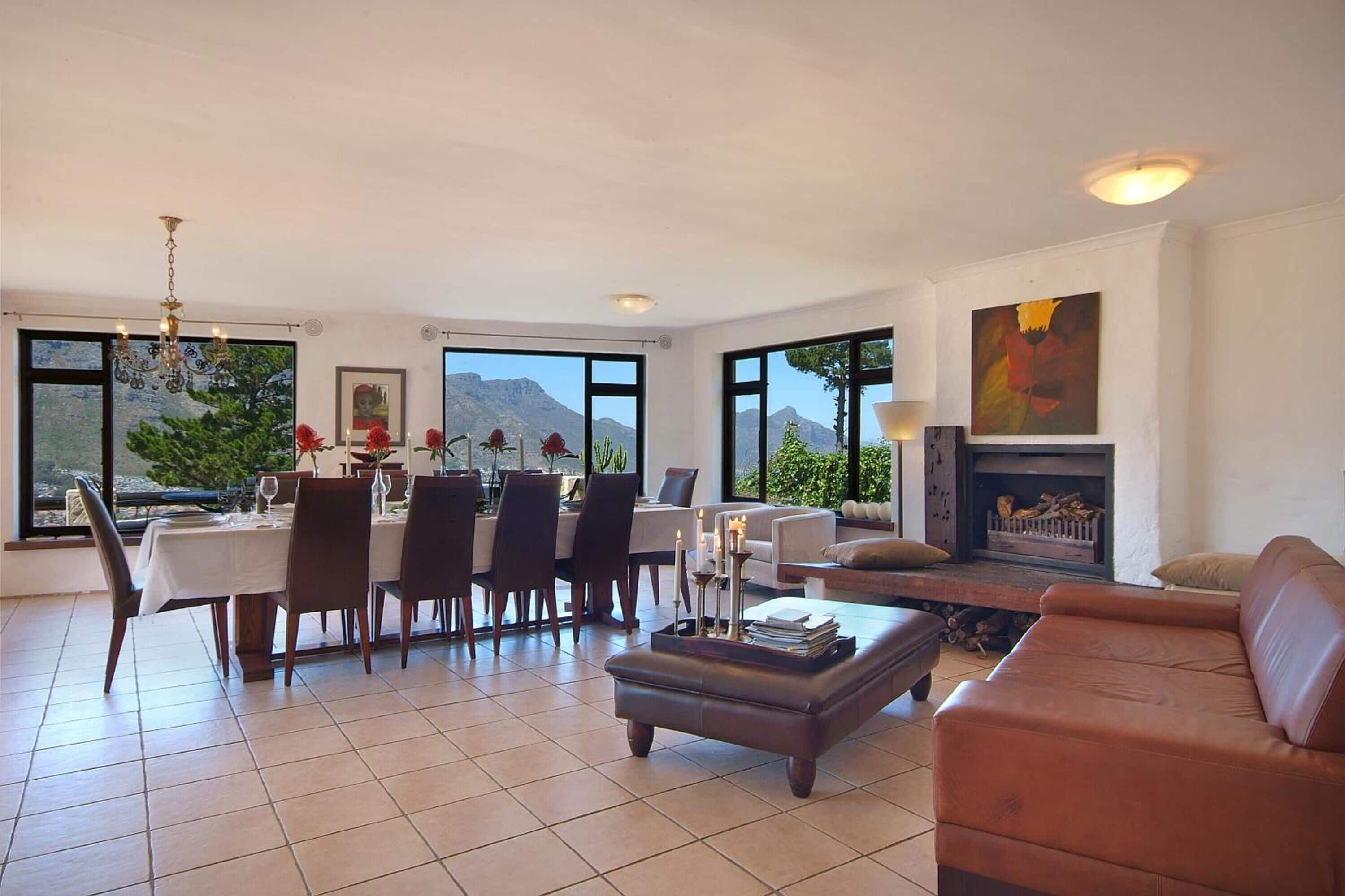 A spacious living area with a dining table set for four, a leather sofa, and a fireplace.