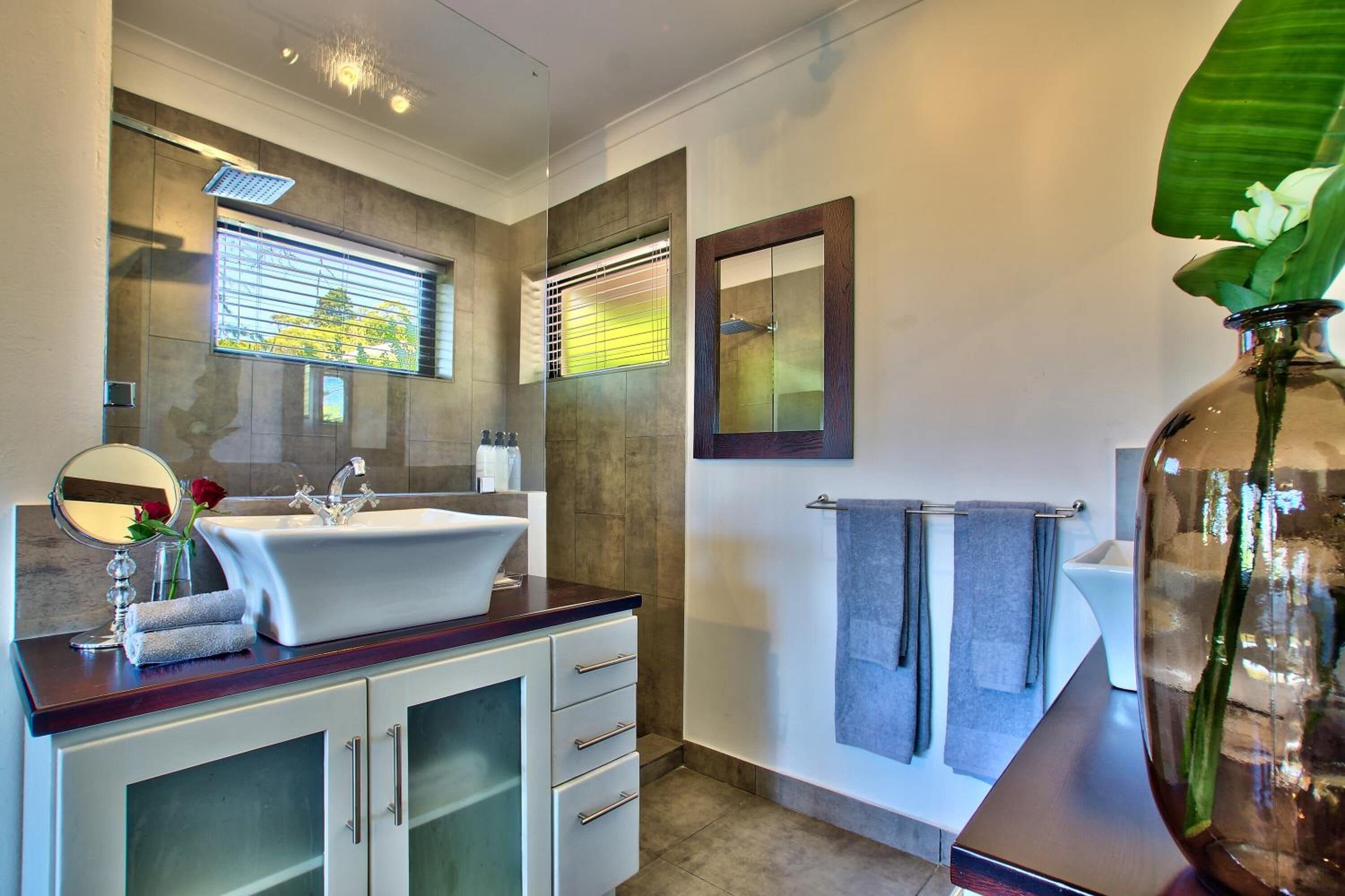 Un baño moderno con un lavamanos grande, espejo y perchero.