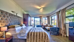 A hotel room with a large bed, a sofa, a TV, and a view of the mountains.