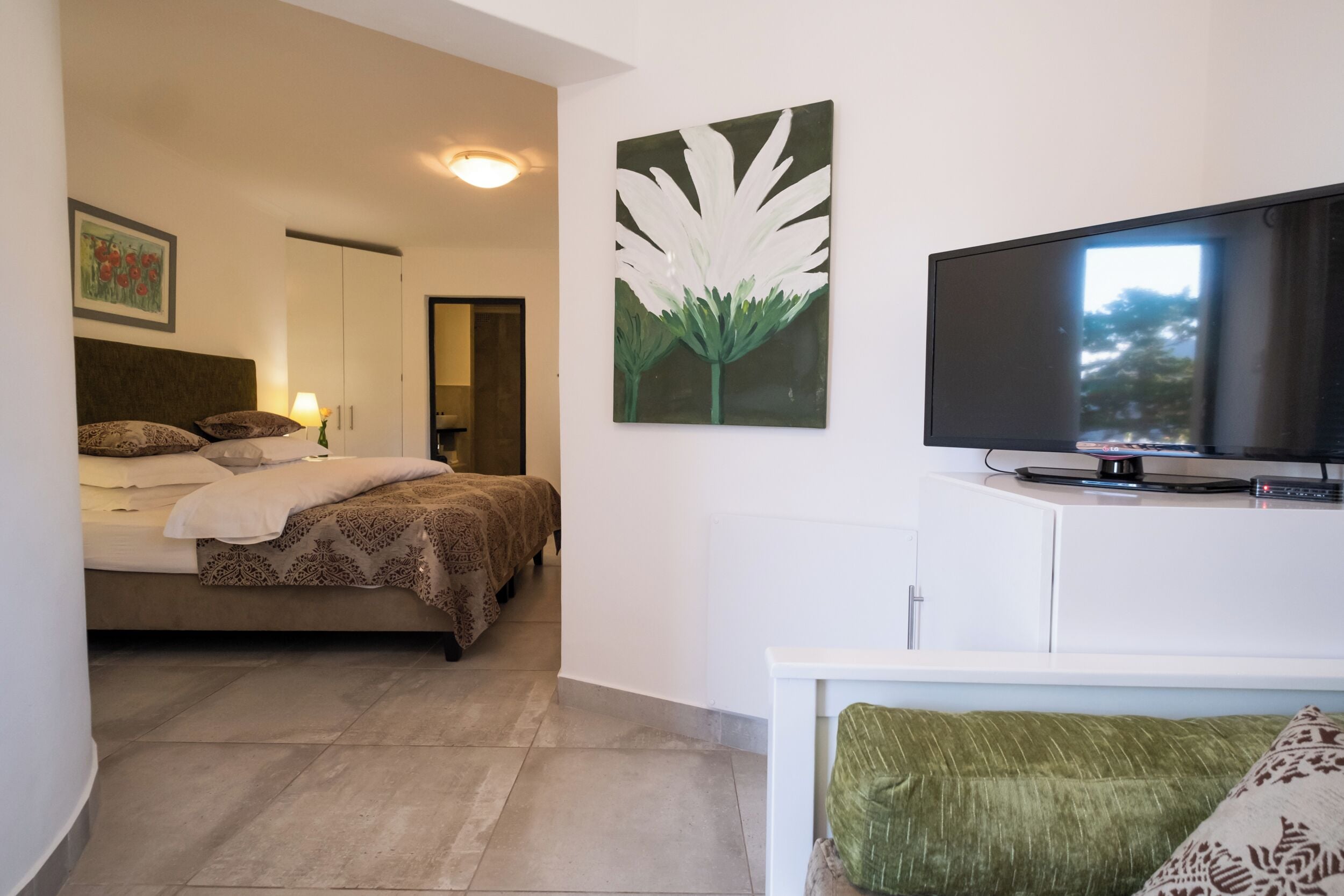 Un dormitorio con una cama, un televisor y un cuadro en la pared.