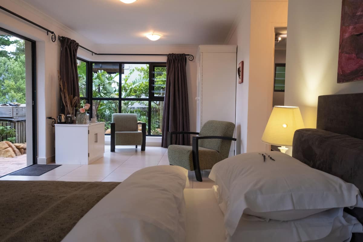 Una habitación de hotel moderna con cama, una silla, un escritorio y vistas al exterior.