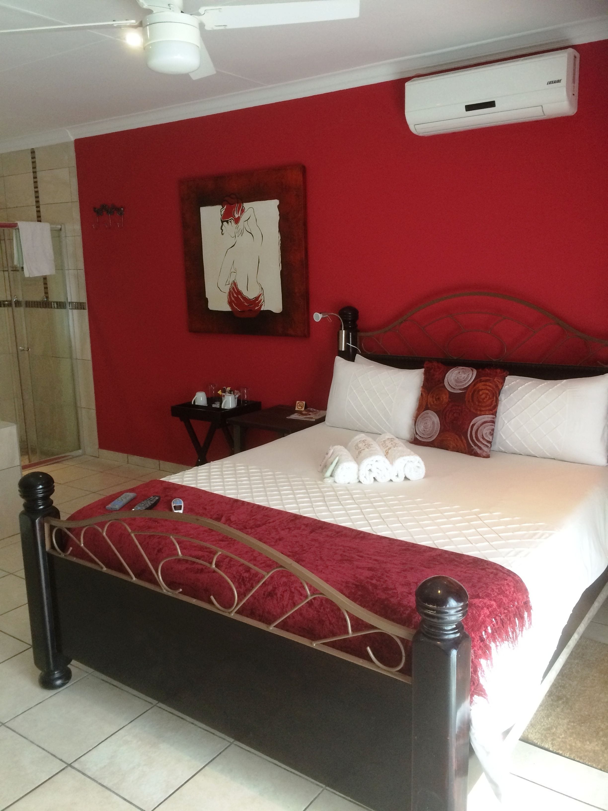 A bedroom with a bed, a nightstand, a wall-mounted air conditioner, and a shower area.