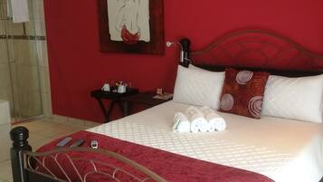 A bedroom with a bed, a nightstand, a wall-mounted air conditioner, and a shower area.
