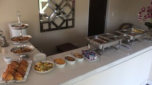 Una mesa de buffet con diversos alimentos y un elemento decorativo en la pared.