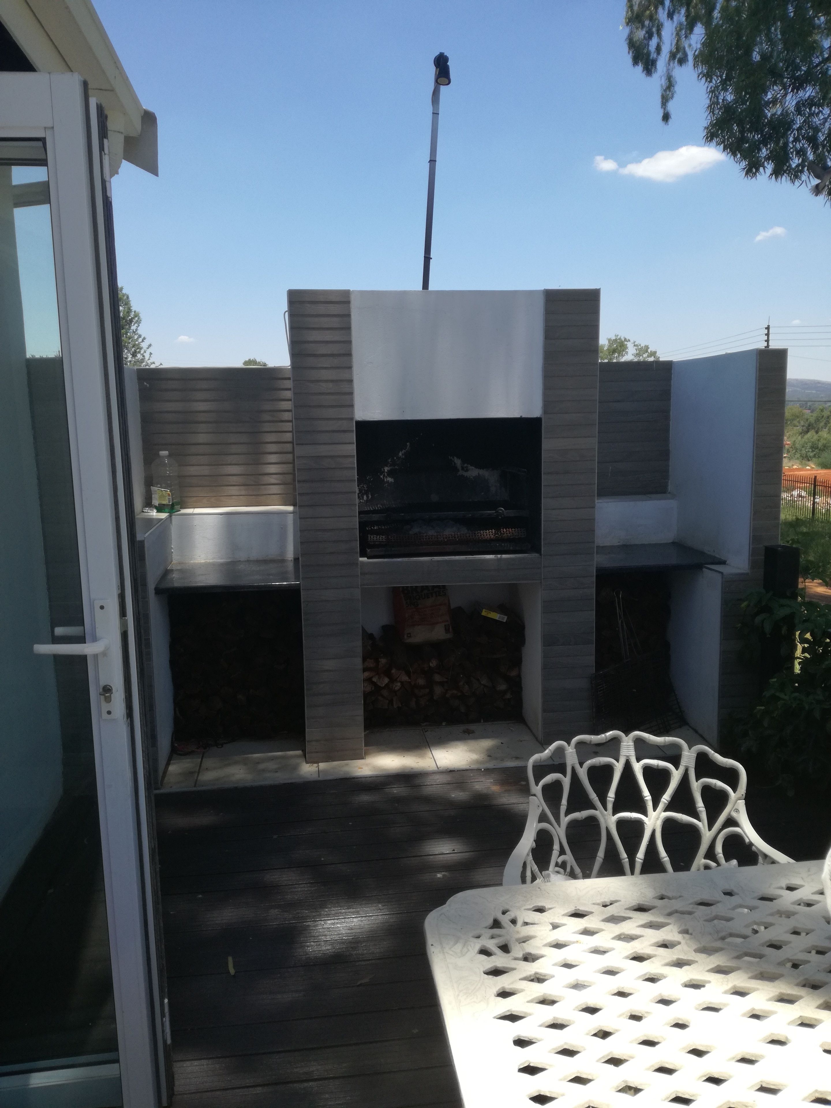 Een buitenbarbecue met een ingebouwde grill, een tafel en een stoel.