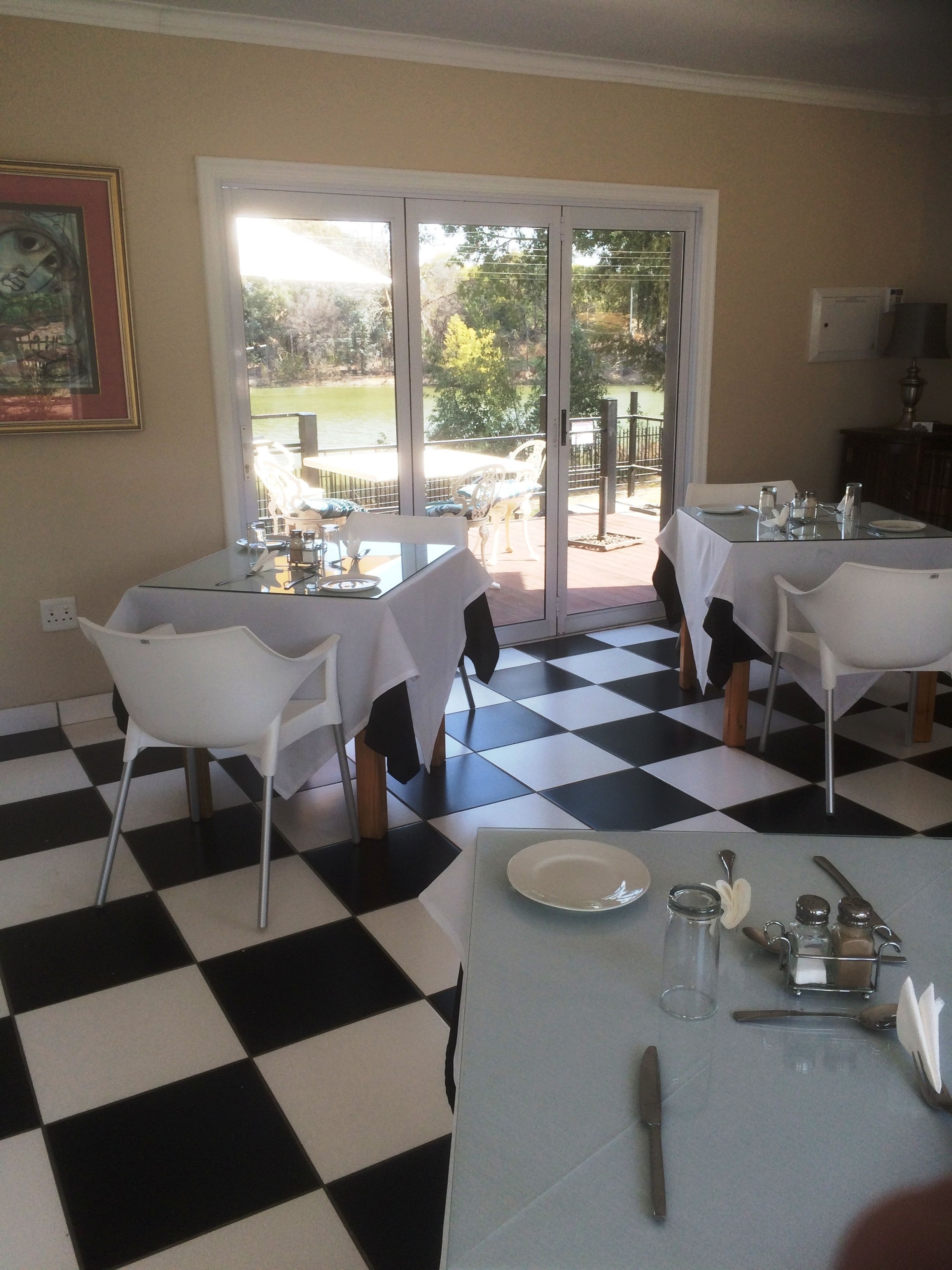 A dining area with a checkered floor, white chairs, and tables set for dining.