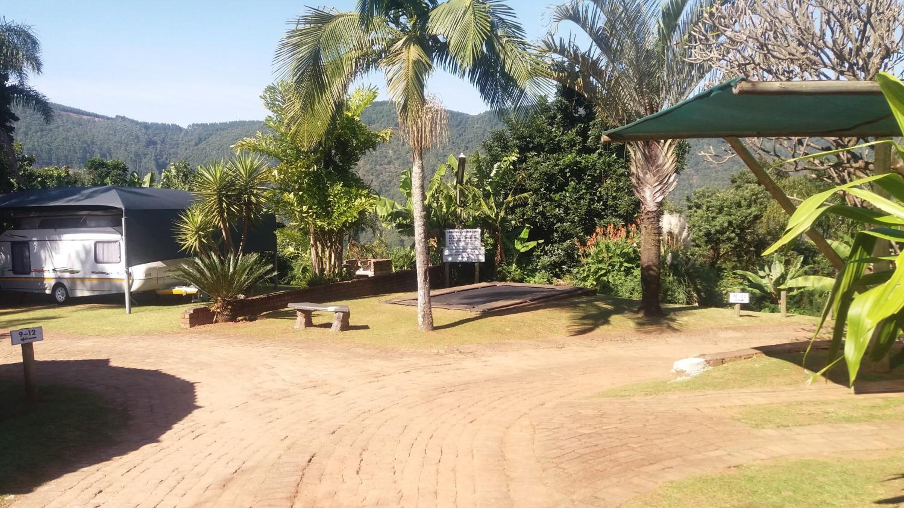 Un campamento con un sendero de tierra, una zona cubierta y una caravana estacionada.