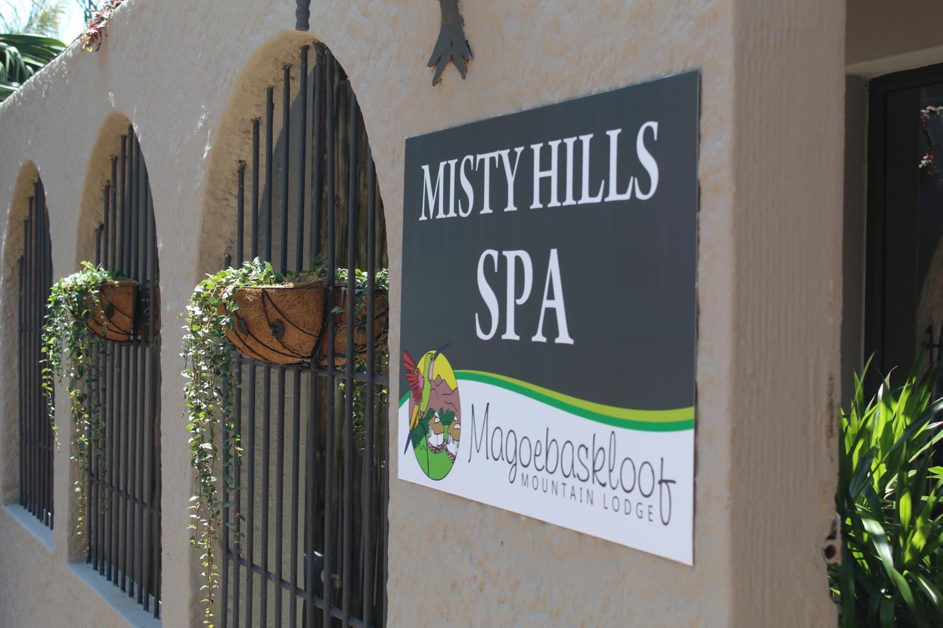 A sign for Misty Hills Spa with a logo for Magoo Backpacker Mountain Lodge.