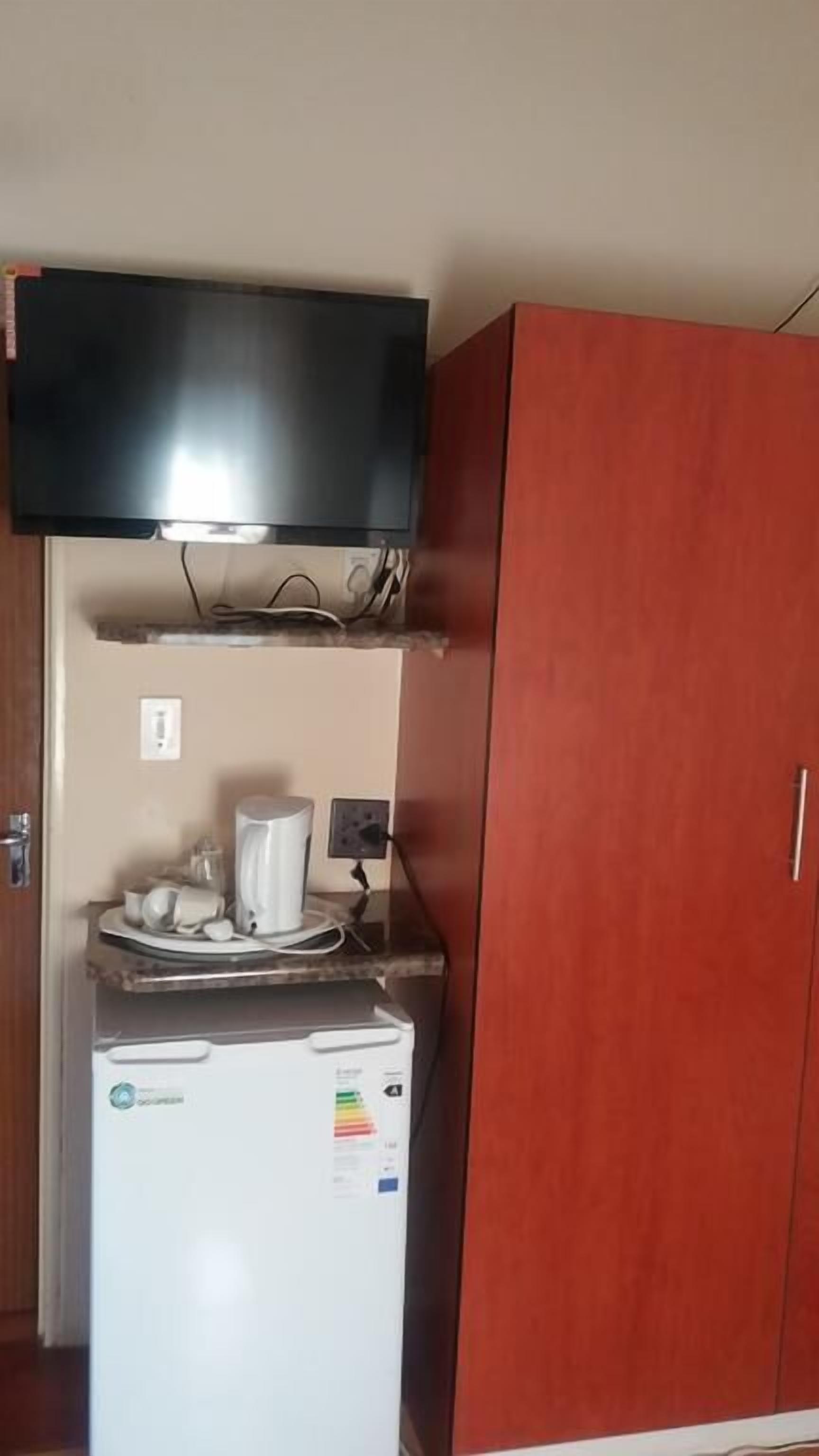 A kitchenette with a microwave, a small refrigerator, a coffee maker, and a flat-screen TV mounted above the counter.
