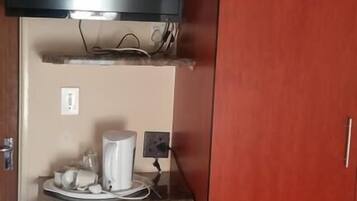 A kitchenette with a microwave, a small refrigerator, a coffee maker, and a flat-screen TV mounted above the counter.