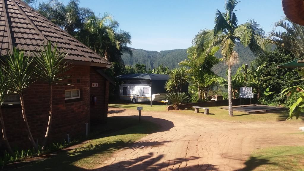 A rustic building with a brick exterior and a tiled roof, surrounded by lush greenery and palm trees.