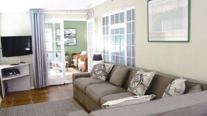 A living room with a beige sofa, a flat-screen TV, and a framed picture on the wall. - 16 On Main Arniston (Arniston)
