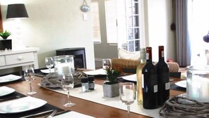 A dining area with a table set for a meal, wine bottles, glasses, and a potted plant. - 16 On Main Arniston (Arniston)