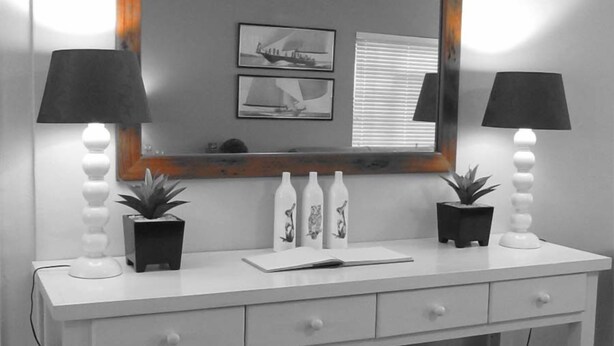 A white vanity with two black lamps, a mirror, and three potted plants. - 16 On Main Arniston (Arniston)