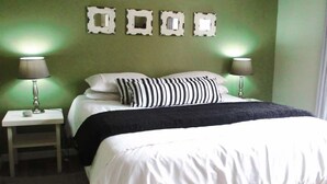 A hotel room with a bed, two bedside lamps, a nightstand, and a wall with decorative frames. - 16 On Main Arniston (Arniston)