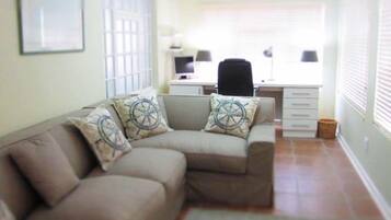 Una sala de estar con un sofá, un escritorio y una silla.