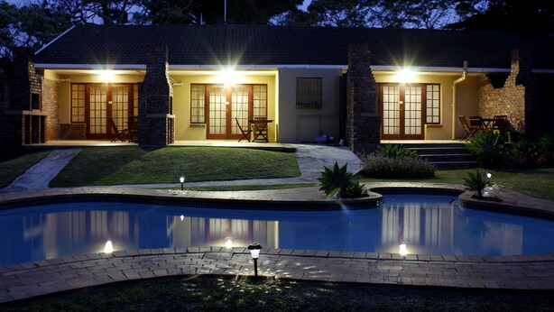 Ein Haus mit Swimmingpool, einem gepflegten Rasen und einem gepflasterten Weg zum Eingang.