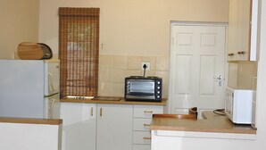 Eine kleine Küche mit Kühlschrank, Toasterofen, Mikrowelle und Holzausstattung.