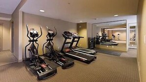 Ett gym med löpband, motionscyklar och en vägg täckt med speglar.