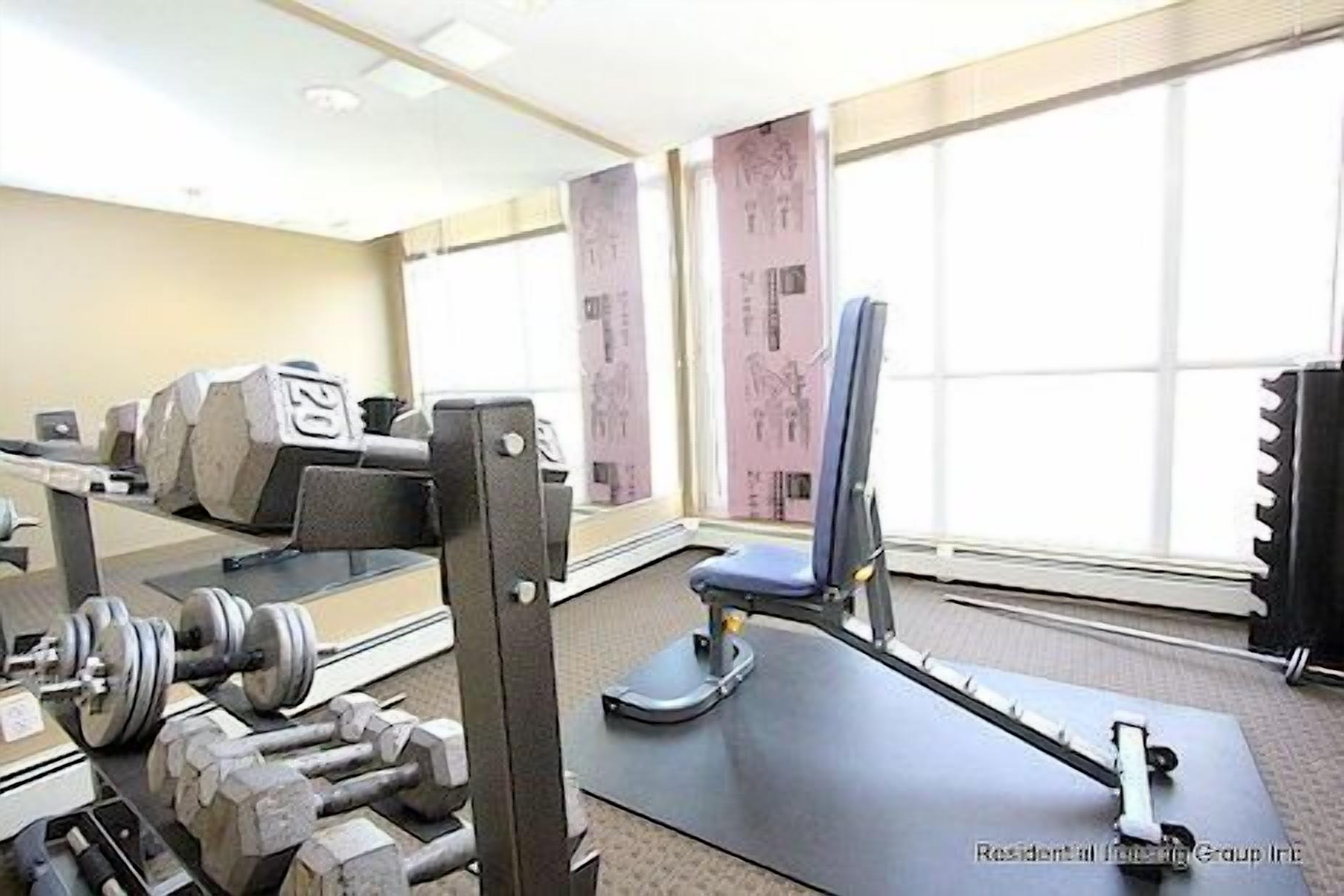 A gym with exercise equipment, a weight bench, and a rowing machine.