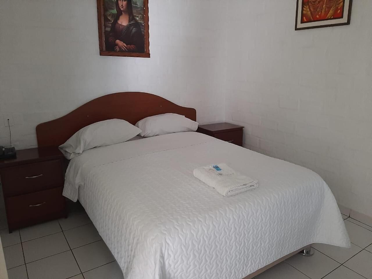 A neatly made bed with a white quilt, a wooden headboard, and two bedside tables with drawers.