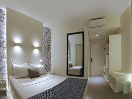 Una habitación de hotel moderna con una cama grande, lámparas de noche, un espejo, un aire acondicionado y un armario.