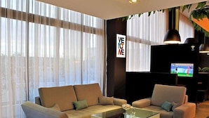 Ein modernes Wohnzimmer mit einer Eckcouch, einem Glastisch und einem flachbildfernseher an der Wand.