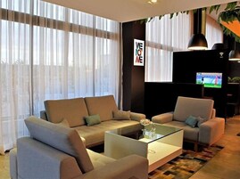 Una sala de estar moderna con un sofá seccional, una mesa de centro de vidrio y un televisor de pantalla plana montado en la pared.