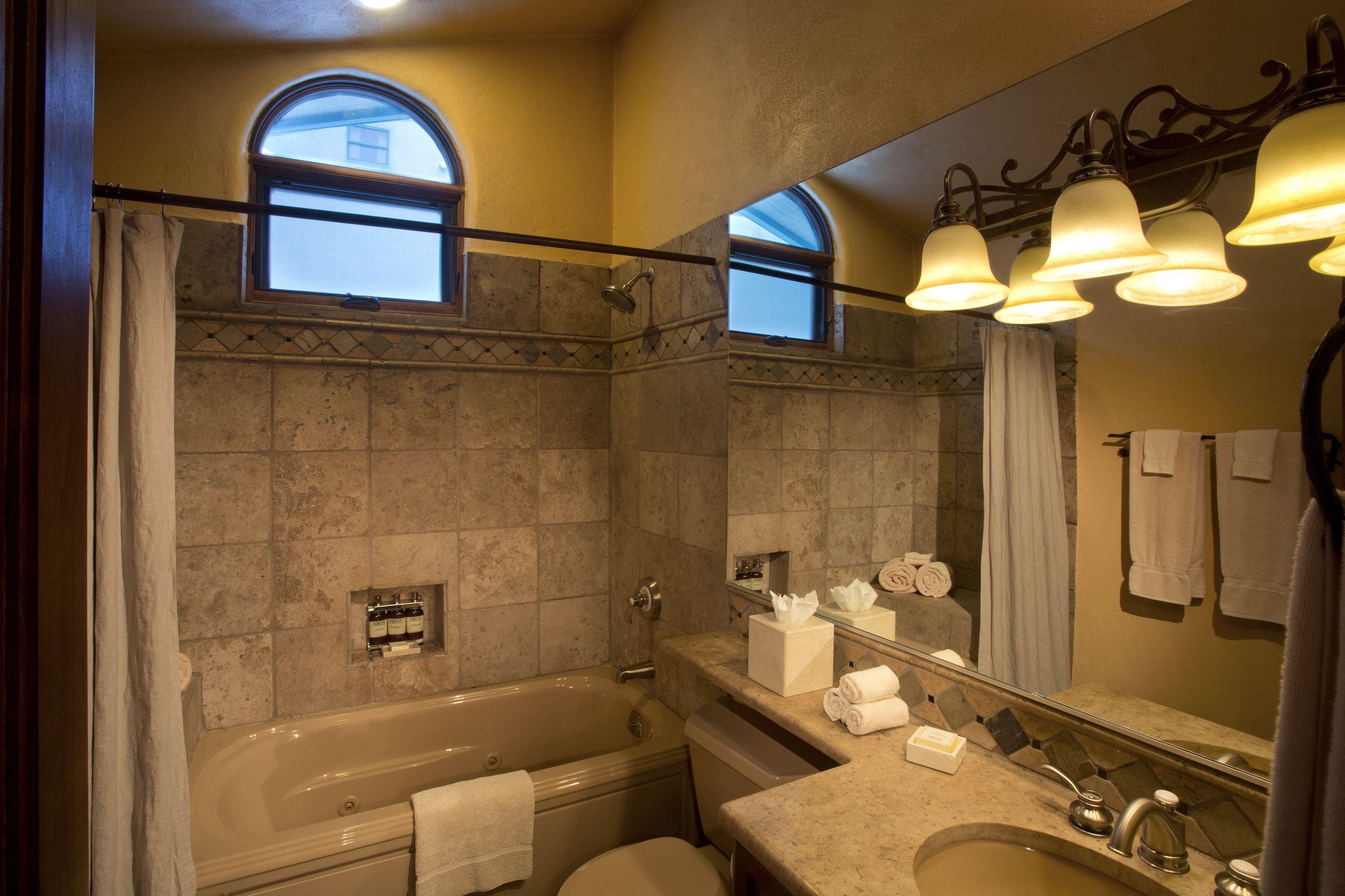 Une salle de bain avec une baignoire, un lavabo et un miroir de coiffeuse.